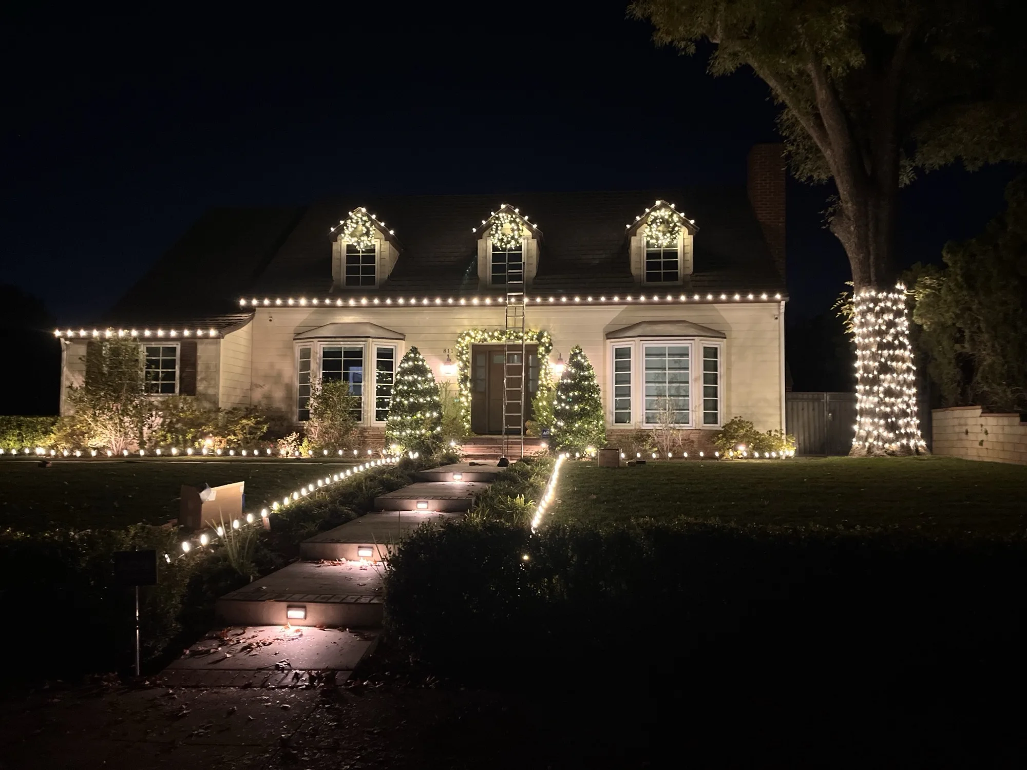 Bee Merry crew installing warm-white roofline lights and dormer wreaths on a Conejo Valley Cape Cod home