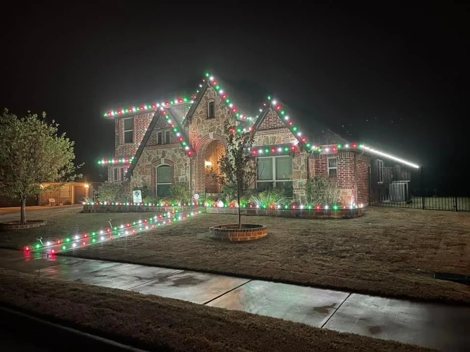 Stone home and landscape lit with red, green and white Christmas lights by Bee Merry